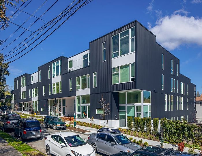Contemporary apartment building with modern design and large windows, set in a vibrant neighborhood with convenient street parking.