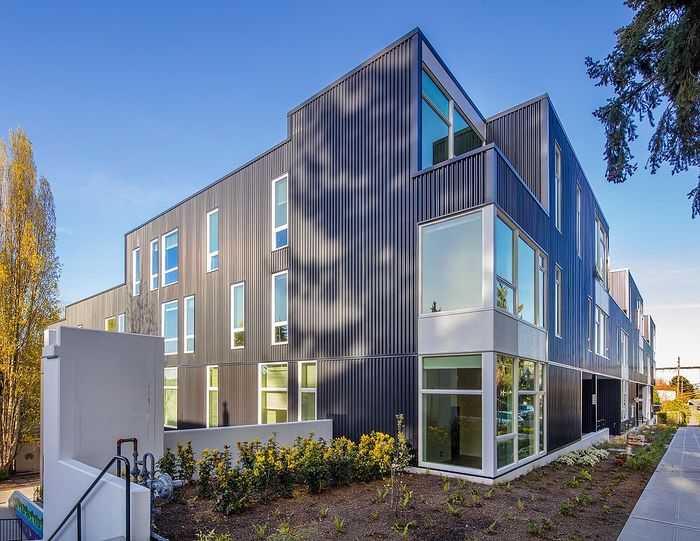 Modern apartment building with sleek design, large windows, and landscaped surroundings.
