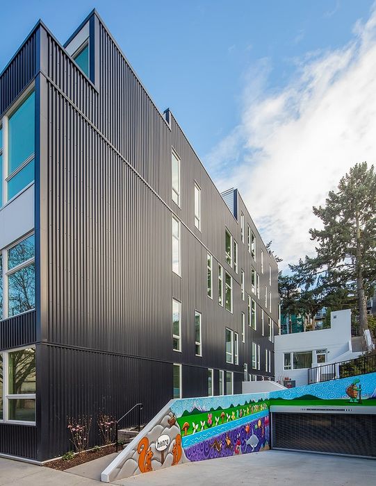 Modern apartment building with sleek black facade and vibrant mural, capturing urban elegance and artistic flair.