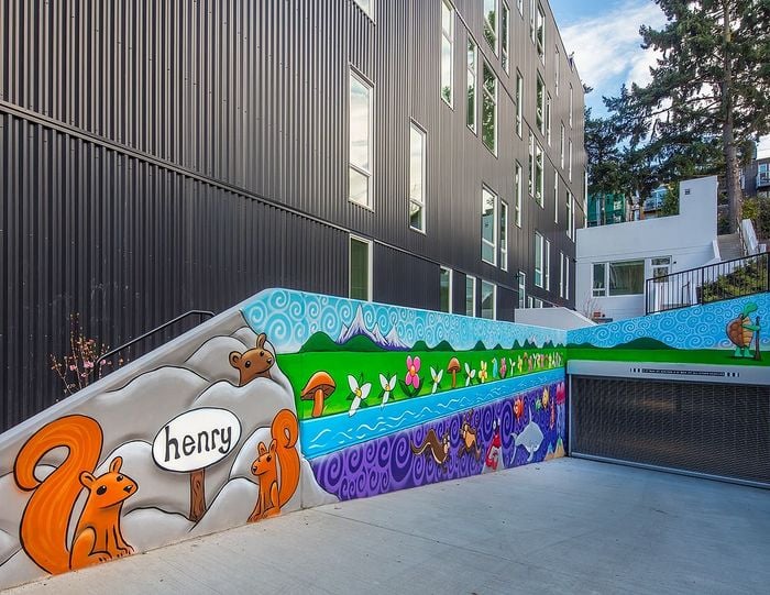 Vibrant mural depicting playful squirrels and colorful nature scenes on a modern apartment building exterior.