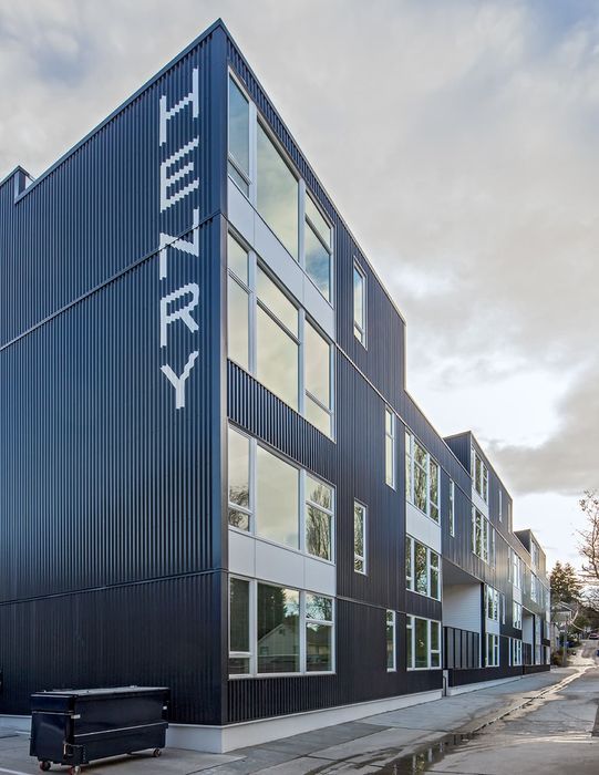 Contemporary apartment building with sleek corrugated metal facade and large windows, showcasing modern urban architecture.