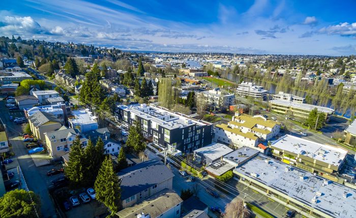 Stunning aerial view of a vibrant neighborhood with modern apartment complexes and lush greenery under a clear blue sky.
