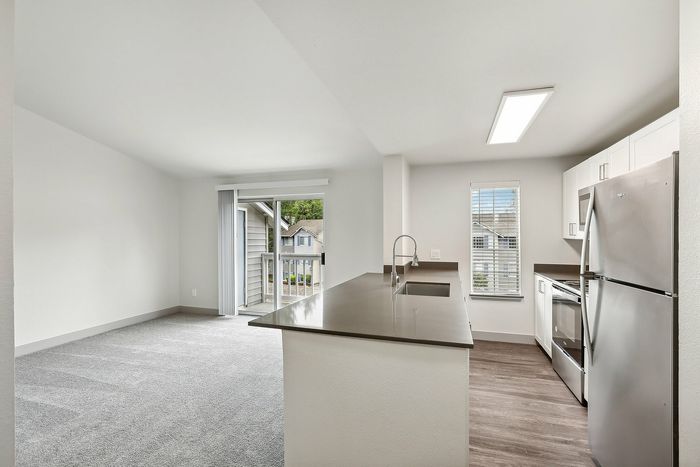 Modern open-concept kitchen and living area with sleek countertops, stainless steel appliances, and a bright view of the outdoors.