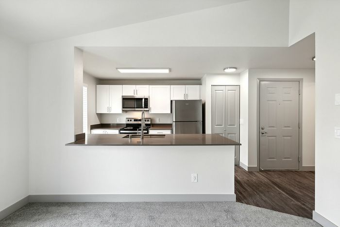 Modern kitchen with sleek countertops, stainless steel appliances, white cabinets, and open-concept design.