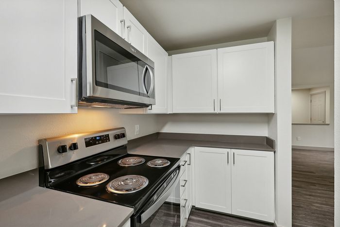Modern kitchen with sleek white cabinetry, stainless steel appliances, and elegant countertops, perfect for culinary enthusiasts.
