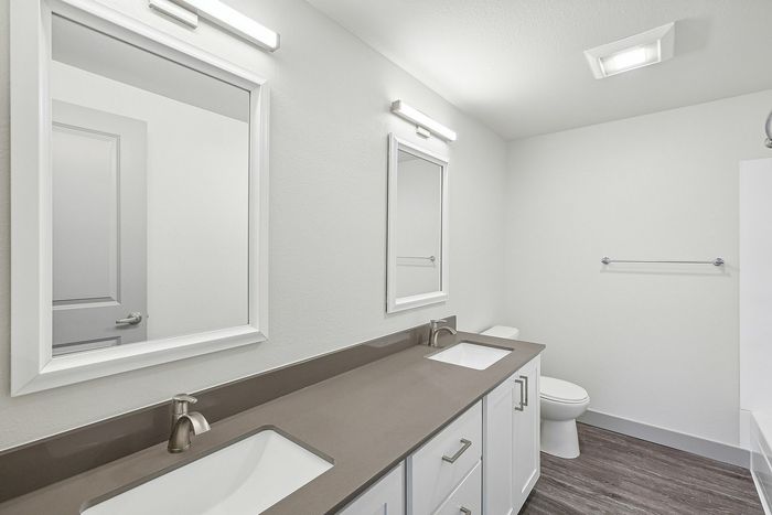 Modern bathroom with dual sinks, sleek countertops, and elegant lighting, showcasing contemporary design.