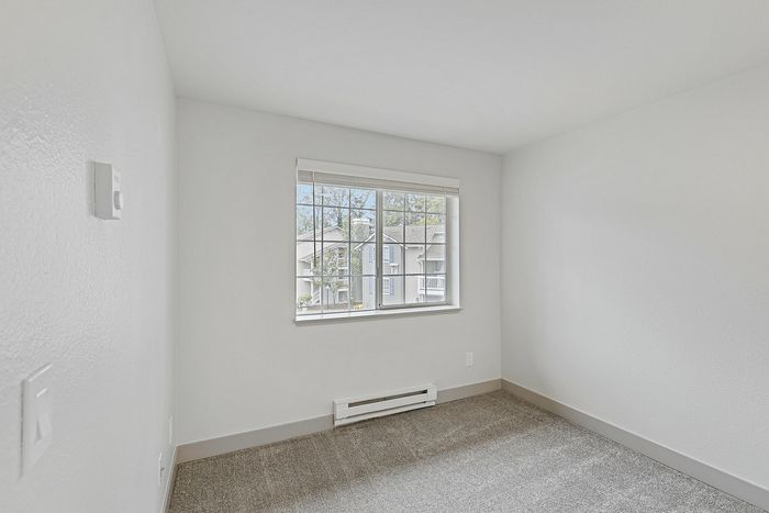 Bright and cozy bedroom with a large window offering serene neighborhood views, perfect for relaxation.