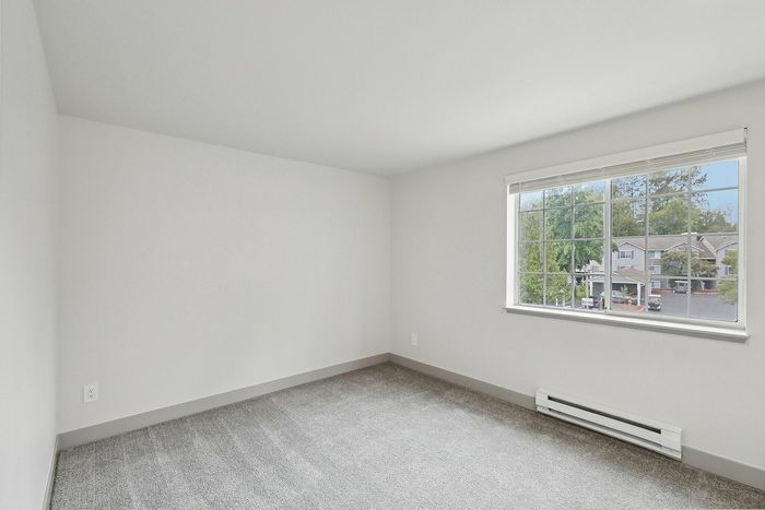 Bright and spacious room with plush carpeting and large window offering a scenic neighborhood view.