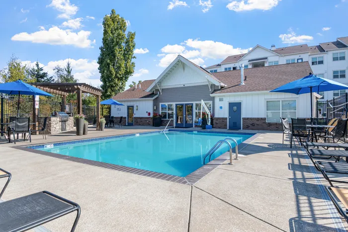 Inviting outdoor pool area with modern patio furniture and umbrellas, perfect for relaxation and entertaining.