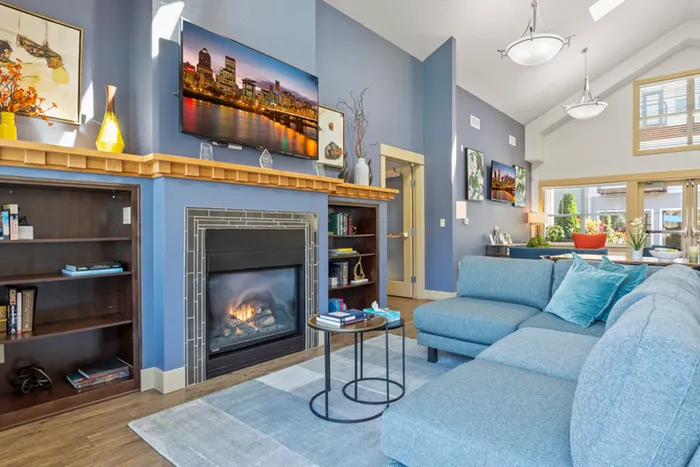 Inviting lounge with cozy fireplace, modern blue sofa, and elegant decor, bathed in natural light from large windows.