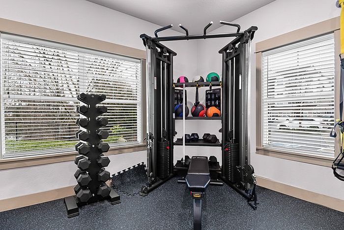 Modern apartment fitness center featuring state-of-the-art gym equipment, bright windows, and sleek flooring.