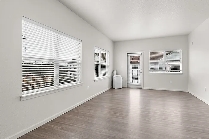 Bright and spacious living area with modern wood flooring and ample natural light from large windows.