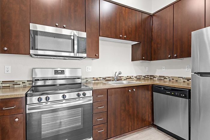 Modern kitchen with sleek stainless steel appliances, elegant dark wood cabinetry, and stylish tile backsplash.