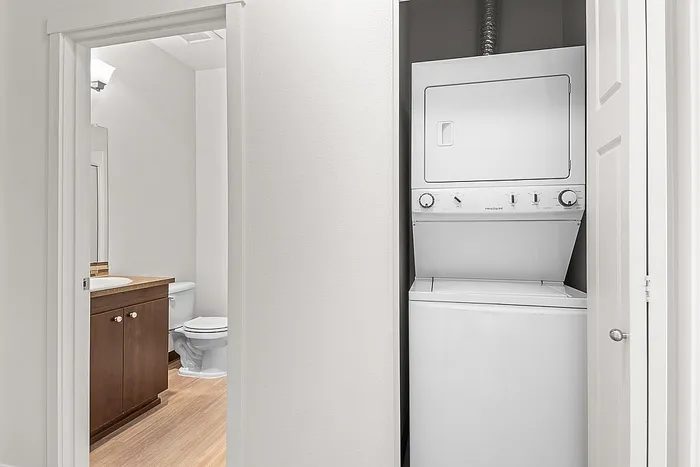 Modern apartment featuring an in-unit stacked washer and dryer adjacent to a sleek bathroom with dark wood cabinetry.
