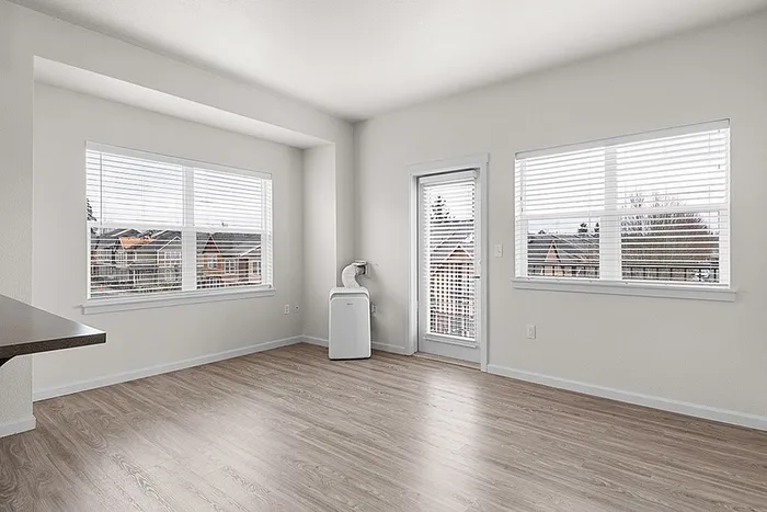 Bright, modern living space featuring large windows, sleek flooring, and a private balcony. Perfect for natural light lovers.