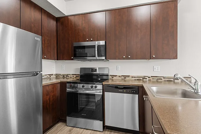 Modern kitchen featuring sleek stainless steel appliances, rich wood cabinetry, and contemporary tile backsplash.