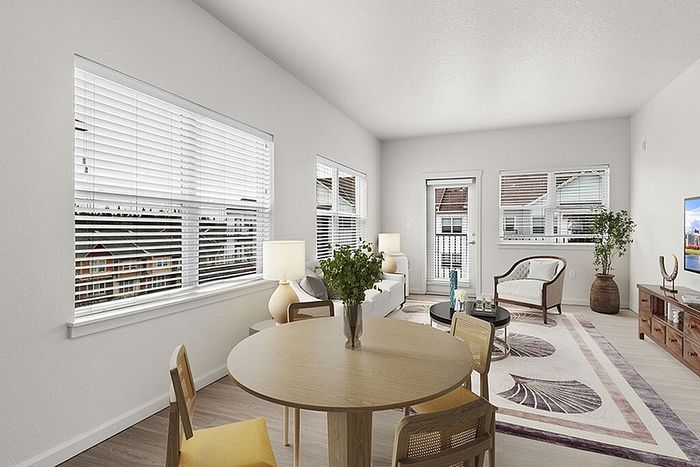 Bright and airy living room with elegant decor, showcasing large windows, a cozy sitting area, and a modern dining space.