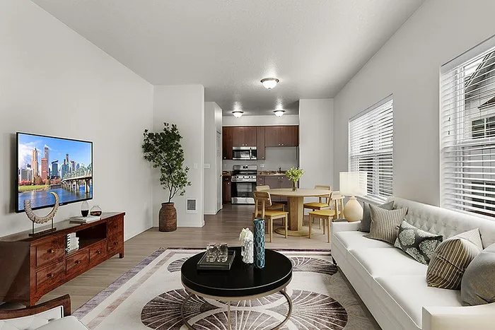 Bright and modern open-concept living area with stylish decor, featuring a cozy sofa, sleek dining set, and a pristine kitchen with stainless steel appliances.