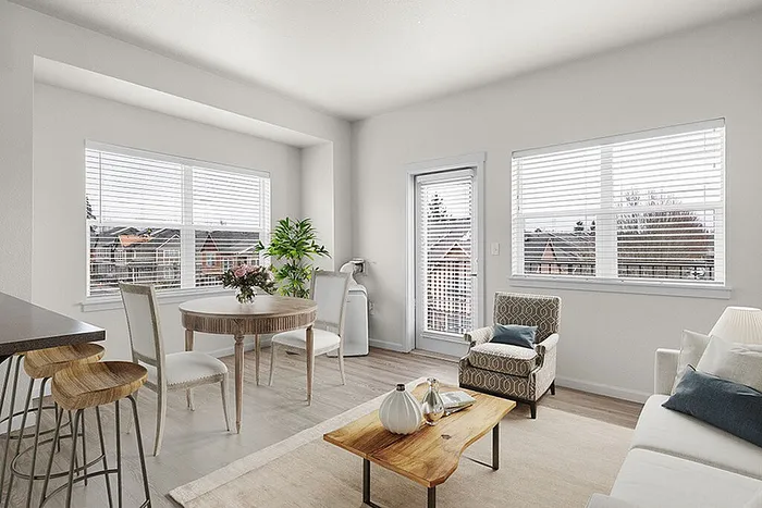 Bright and inviting living area with large windows, modern decor, and a cozy dining space, offering scenic views and abundant natural light.