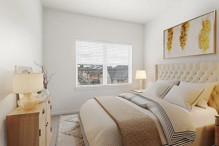 Inviting bedroom with plush bedding, elegant artwork, and abundant natural light through a large window.