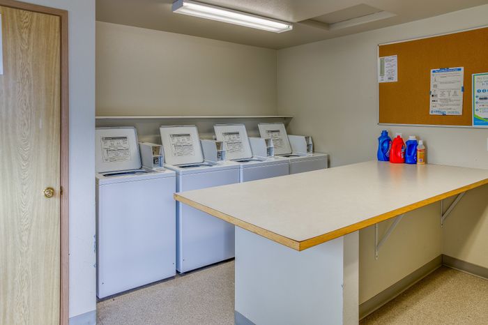Modern laundry room with four efficient washing machines and spacious folding counter, perfect for convenient and organized living.
