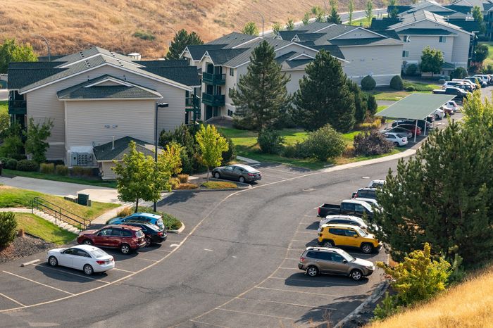 Charming hillside apartment complex with green spaces, ample parking, and scenic views.