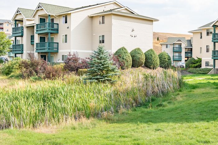 Charming apartment complex surrounded by lush greenery and well-maintained landscapes, offering serene living spaces with private balconies.