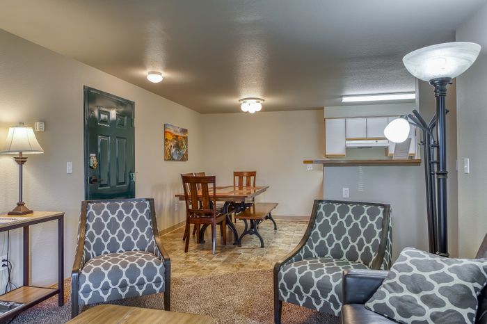 Inviting open-plan living and dining area featuring stylish patterned chairs, elegant wooden dining set, and warm lighting, ideal for entertaining.