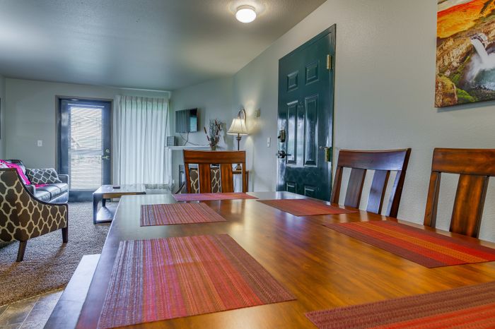 Charming living and dining area with elegant wooden furnishings, vibrant decor accents, and modern lighting, offering a welcoming and stylish atmosphere.