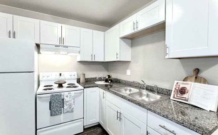 Modern kitchen with sleek white cabinetry, granite countertops, and updated appliances for a functional and stylish cooking space.