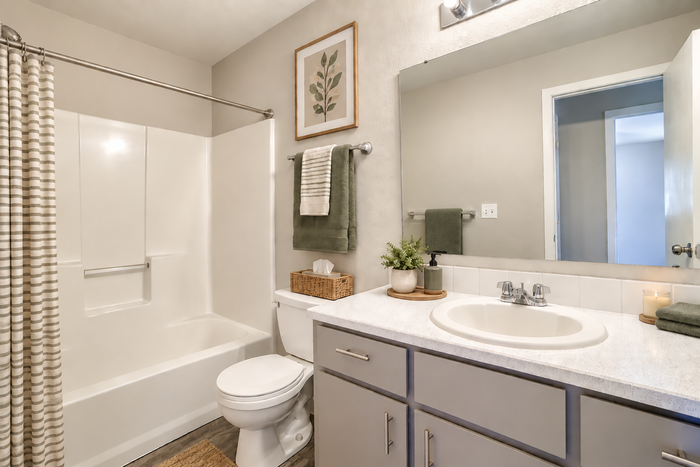 Modern bathroom featuring elegant fixtures, a cozy bathtub, and stylish decor with earthy green accents.