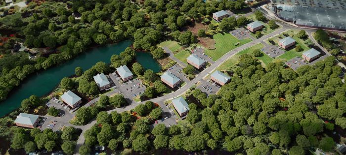 Aerial view of Westgate Arms in Salem, New Hampshire showing apartment buildings, parking areas, and scenic river surrounded by wooded landscape