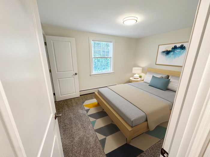Cozy bedroom with natural light, soft carpet flooring, and modern furnishings at Westgate Arms apartments in Salem, New Hampshire