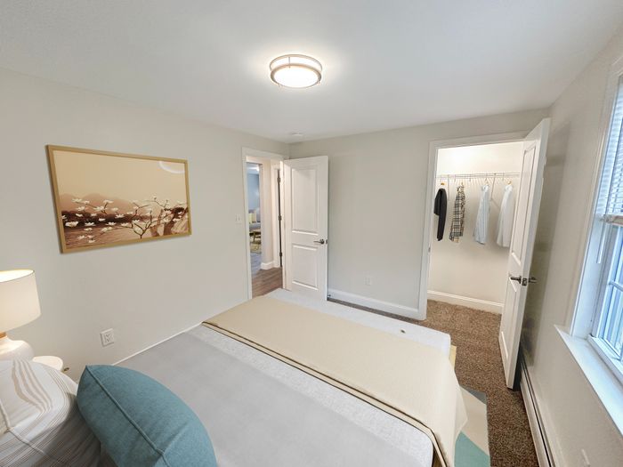 Spacious bedroom with large window, walk-in closet, and soft carpet flooring at Westgate Arms apartments in Salem, New Hampshire