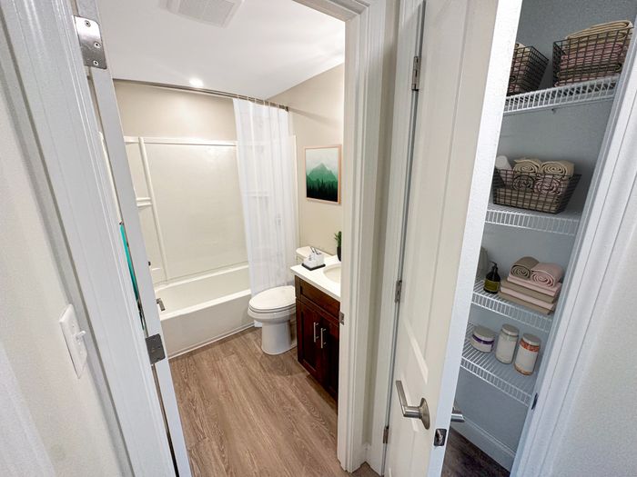 Full bathroom with tub and shower, wood-style flooring, and adjacent linen closet at Westgate Arms apartments in Salem, New Hampshire