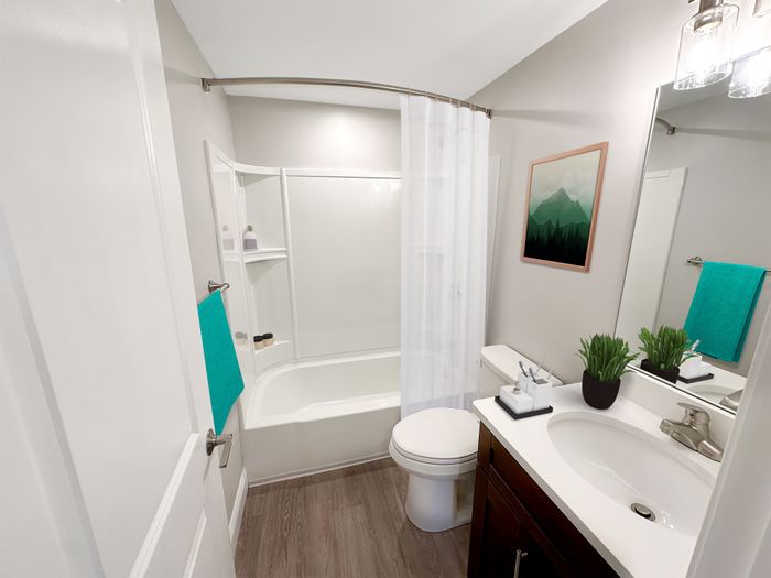 Modern bathroom with tub and shower, vanity sink, and wood-style flooring at Westgate Arms apartments in Salem, New Hampshire
