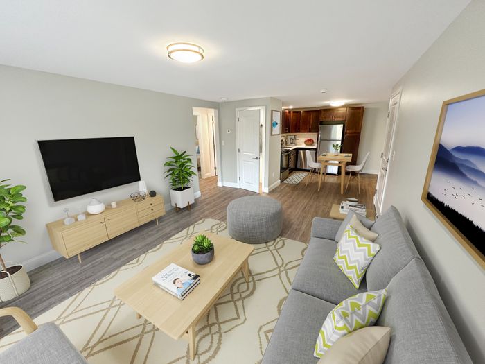 Spacious living room with modern furnishings, open layout, and adjoining kitchen and dining area at Westgate Arms in Salem, New Hampshire
