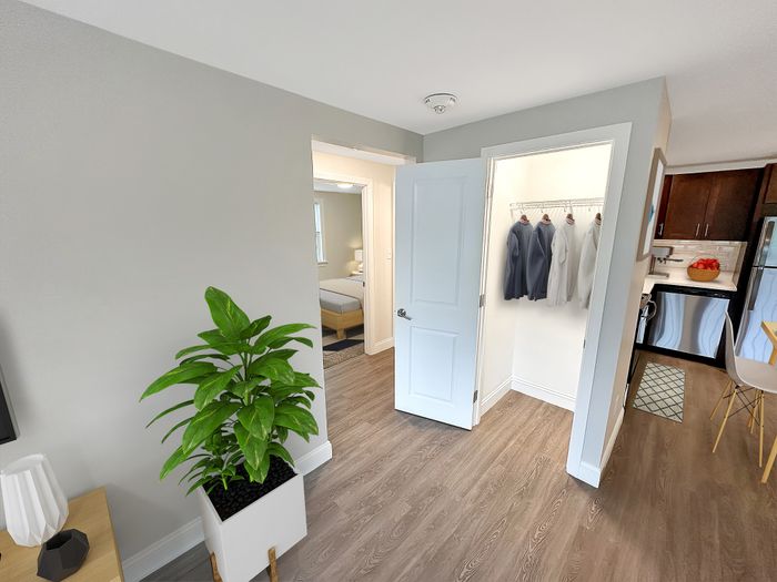 Apartment entryway with coat closet, wood-style flooring, and view into kitchen and bedroom at Westgate Arms in Salem, New Hampshire