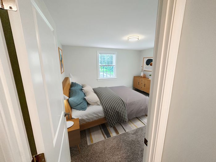 Cozy bedroom with large window, natural light, and plush carpeting in a staged apartment at Westgate Arms in Salem, New Hampshire