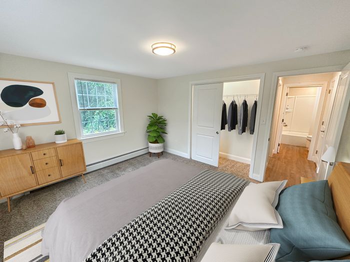 Bright bedroom with large window, walk-in closet, and soft carpet flooring at Westgate Arms apartments in Salem, New Hampshire