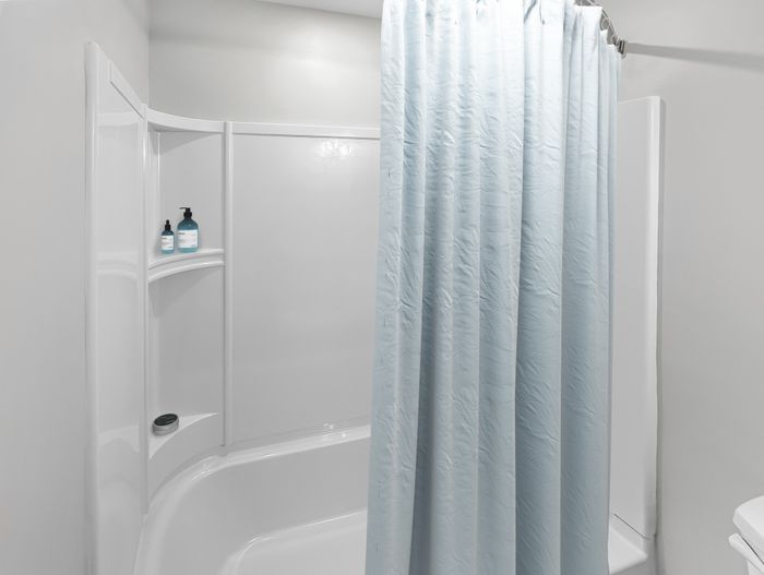 Bathroom with tub and shower combination and built-in shelving in an apartment at Westgate Arms in Salem, New Hampshire