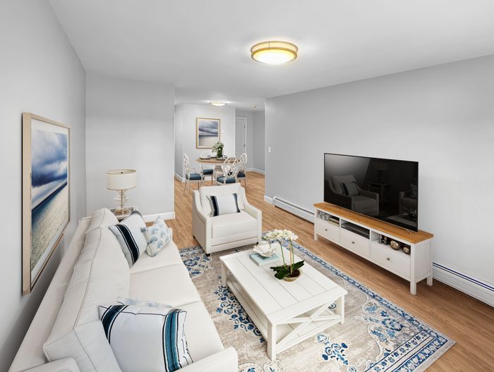 Spacious living room with open layout, hardwood-style flooring, and dining area in a staged apartment at Westgate Arms in Salem, New Hampshire
