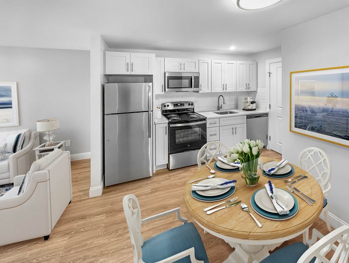 Modern kitchen with white cabinetry, stainless steel appliances, and dining area in a staged apartment at Westgate Arms in Salem, New Hampshire