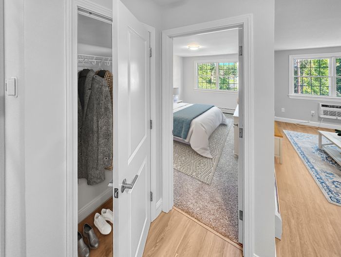 Bedroom with closet space and large windows providing natural light in a staged apartment at Westgate Arms in Salem, New Hampshire