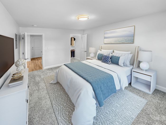 Spacious bedroom with plush carpeting, large bed, and ample closet space in a staged apartment at Westgate Arms in Salem, New Hampshire
