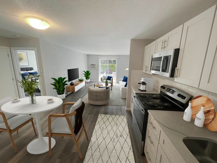 Open-concept apartment kitchen and living room with white cabinetry and balcony access at Woodlands at Nashua