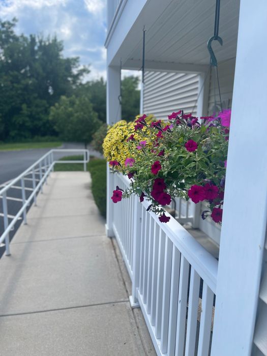 Charming apartment patio with hanging flower baskets and walkway at Allard’s Grove in Dracut, MA