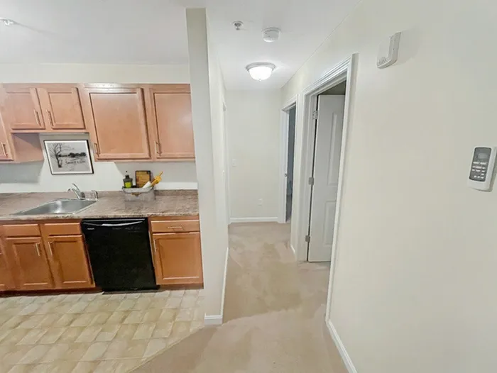 Bright apartment kitchen with adjacent hallway and living space at Allard’s Grove in Dracut, MA