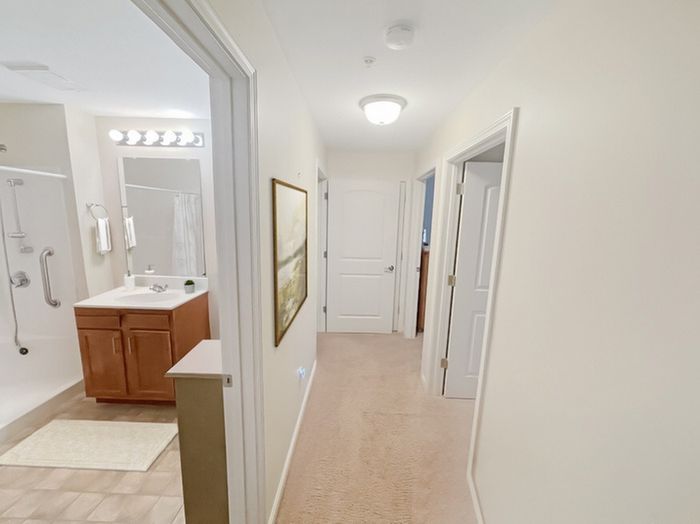 Clean and inviting apartment hallway with adjacent bathroom at Allard’s Grove in Dracut, MA