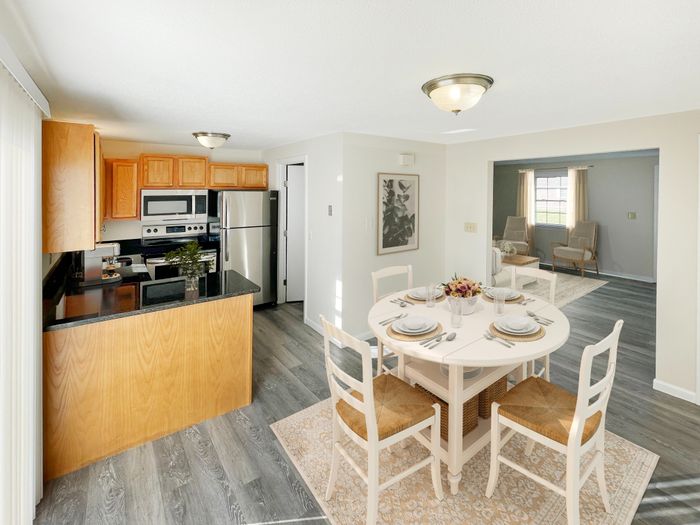 Open kitchen with breakfast bar, stainless steel appliances, and dining area leading to living room at Meadowbrook Village in Gardner, Massachusetts